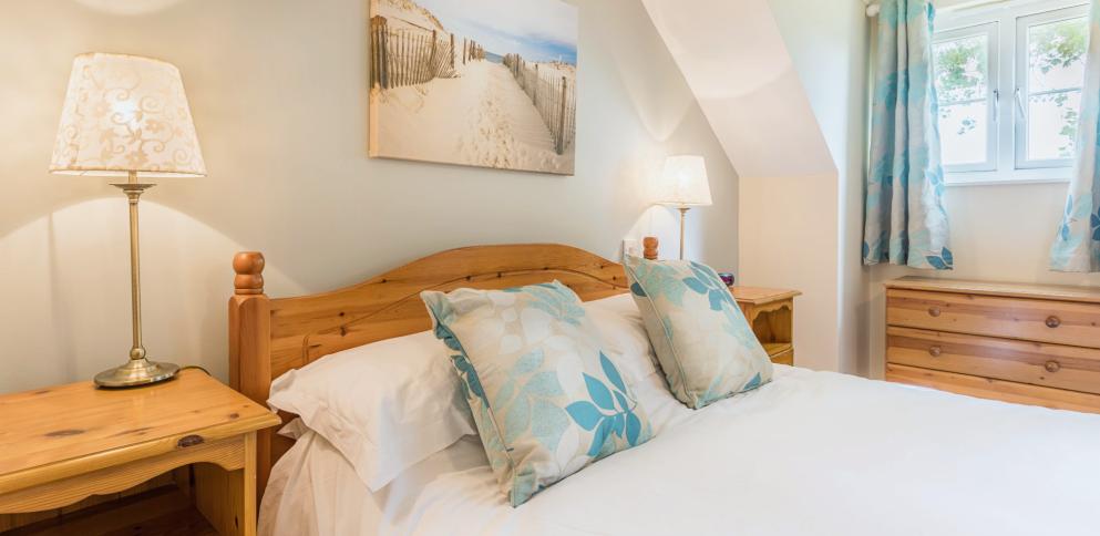 pine bed with white sheets and patterned cushions.  