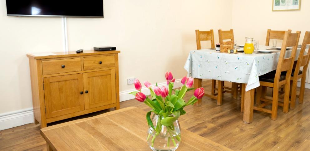 living room with an oak table with pink tulips and breakfast set out on table