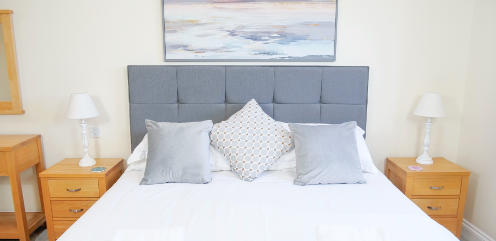 Beautiful super-king bed with grey headboard and large framed picture
