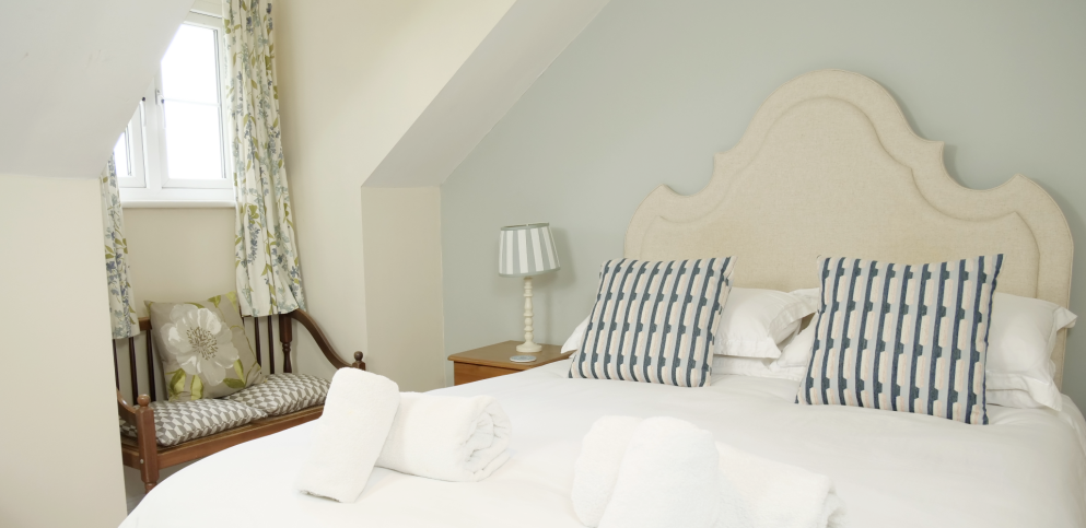 king bed with white sheets and blue striped cushions