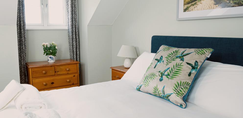 king size bed with navy blue headboard and a cushion with tropical birds
