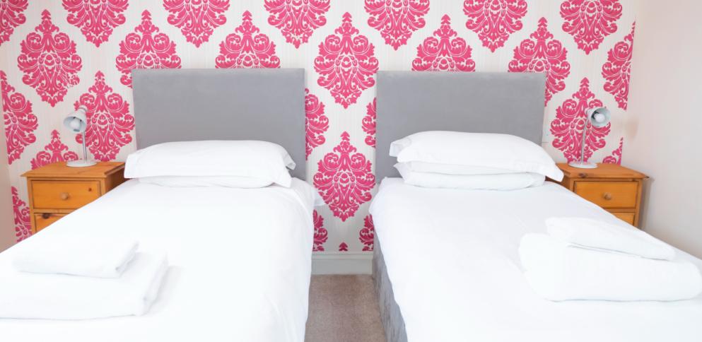 twin bedroom with vibrant hot pink patterned wallpaper