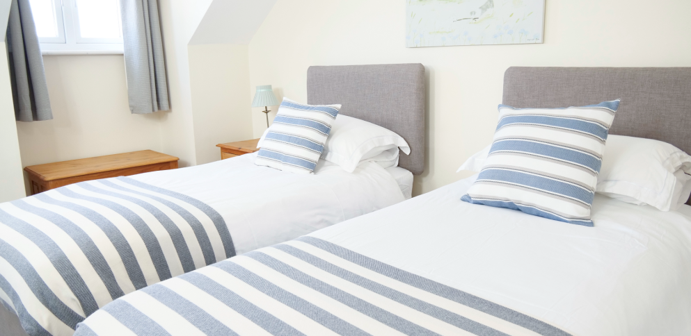 twin beds with blue and cream striped cushions